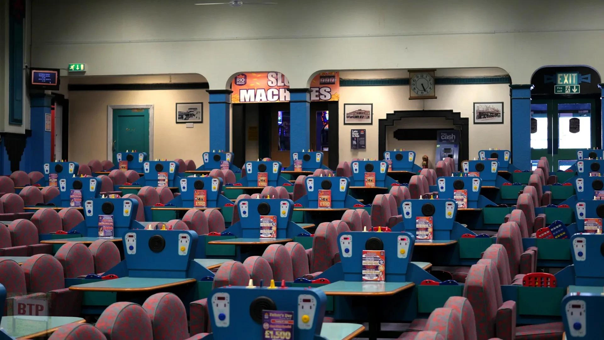 Rows of blue tables and patterned chairs in an empty bingo hall